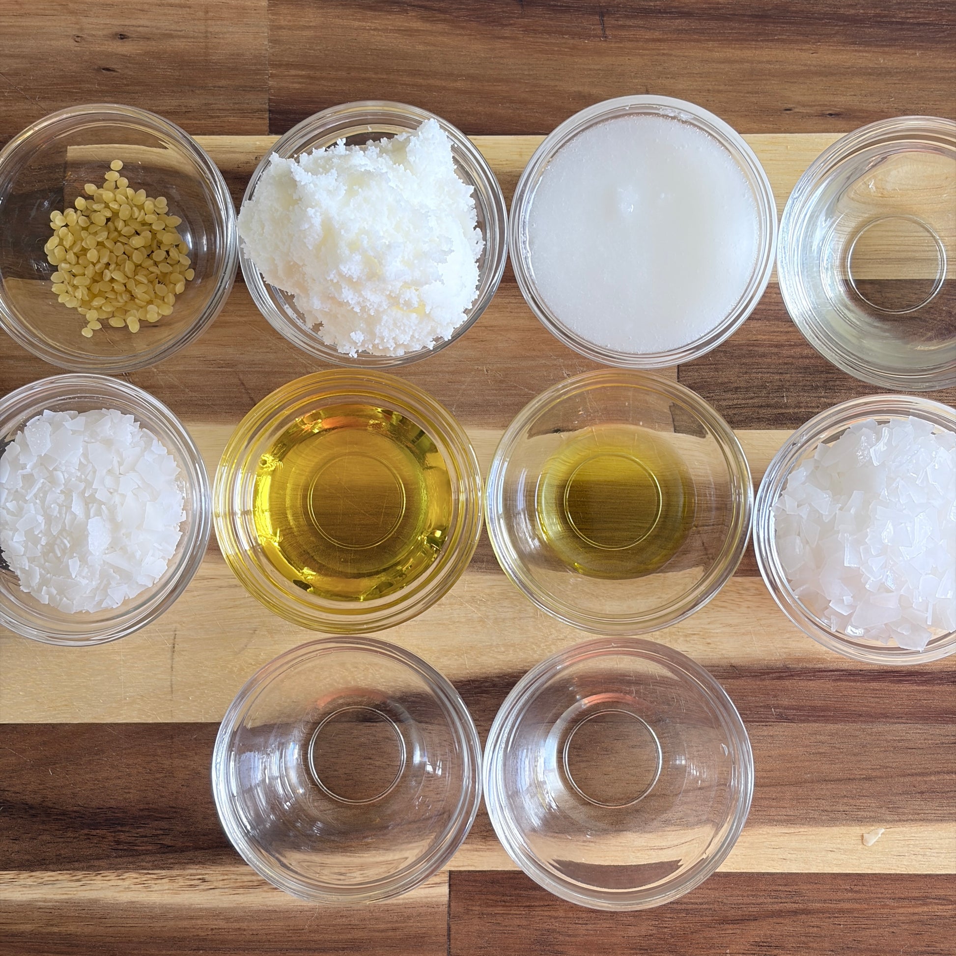 Magnesium Body Butter ingredients on a wooden cutting board. Left to right, top to bottom:

Beeswax, Shea Butter, Coconut Oil, Distilled Water, Olivem 1000, Golden Jojoba Oil, Essential Oil, Magnesium Flakes, Vitamin E, Geogard ECT